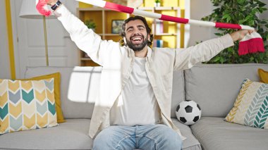 Evdeki kanepede oturan İspanyol futbolu takımını destekleyen genç adam.