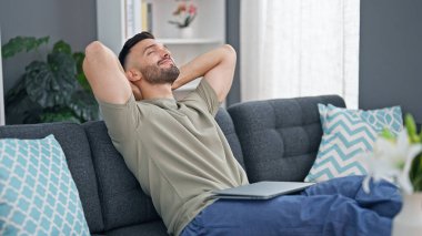 Genç İspanyol adam, ellerini başının üstüne koyup evinde kanepede oturarak rahatladı.