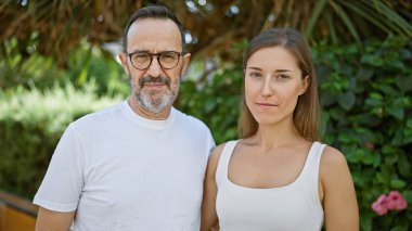 Baba ve kızı parkta beraberler, ciddi yüzlerinde bir sevgi bağı, açık havada serin bir yaşam tarzını ifade ediyorlar yeşil güvenin ortasında.