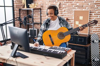Afrikalı Amerikalı kadın müzisyen müzik stüdyosunda klasik gitar çalıyor.
