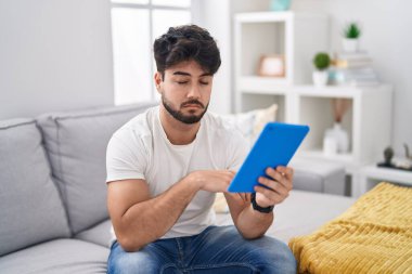 Kanepede oturan dokunmatik sakallı İspanyol adam uykulu ve yorgun görünüyor, yorgunluktan yorgun ve akşamdan kalma, sabahları tembel gözler.. 