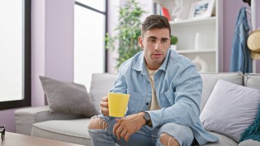 Genç, yakışıklı İspanyol adam sabah espresso 'sunun tadını çıkarıyor, rahat oturma odasındaki kanepede uzanıyor, rahat dairesinde kahve içerken ciddi bir sohbete dalmış..