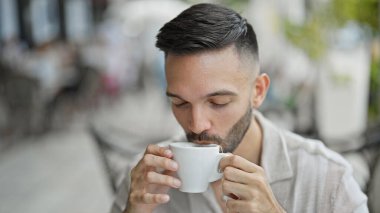 Genç İspanyol adam kahve dükkanının terasında çay içiyor.