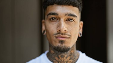 Sokakta ciddi bir ifadeyle dikilen genç Latin adam.