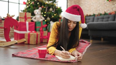 Genç, güzel İspanyol kadın Noel 'i kutluyor. Evdeki defterde yazıyor.