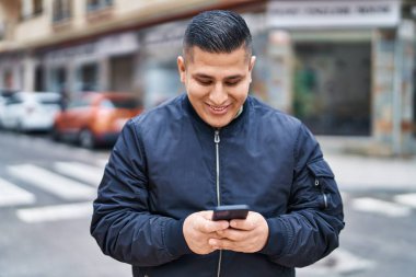 Sokakta akıllı telefon kullanan, kendine güvenen genç Latin adam.