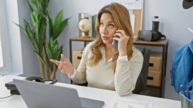 Modern bir ofis ortamında şaşkın görünen İspanyol bir iş kadını.