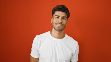 Sakallı, beyaz gömlekli, kırmızı duvara gülümseyen yakışıklı bir İspanyol.