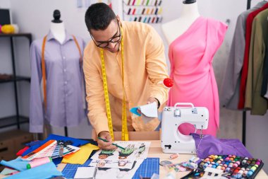Genç İspanyol terzi terzi terzide elbise tasarımı yapıyor.