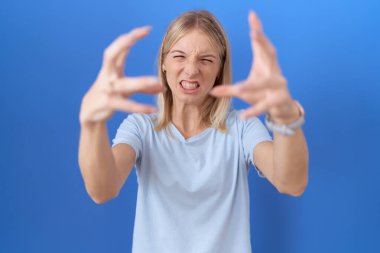 Kafkasyalı genç bir kadın günlük mavi tişört giyip öfkeden bağırıyor, elleri boğmaya çalışıyor, deli gibi bağırıyor. 