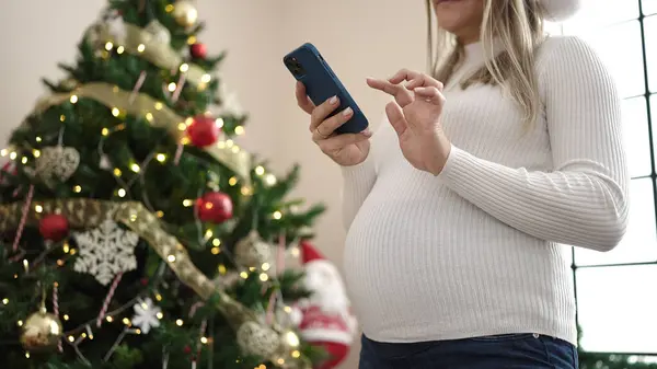 Νεαρή Έγκυος Γυναίκα Που Χρησιμοποιεί Smartphone Γιορτάζει Χριστούγεννα Στο Σπίτι — Φωτογραφία Αρχείου