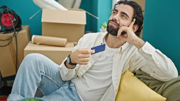 Mladý Hispánec Drží Kreditní Kartu Sedí Pohovce Myšlení Novém Domově — Stock fotografie