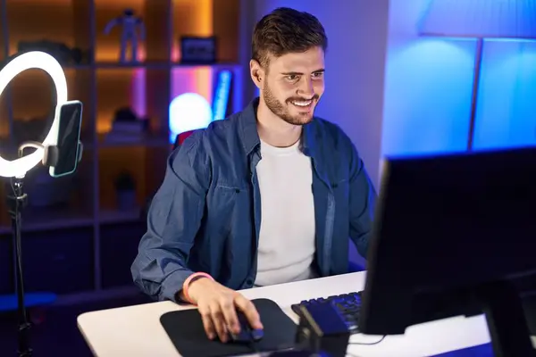 Young caucasian man streamer playing video game using computer at gaming room