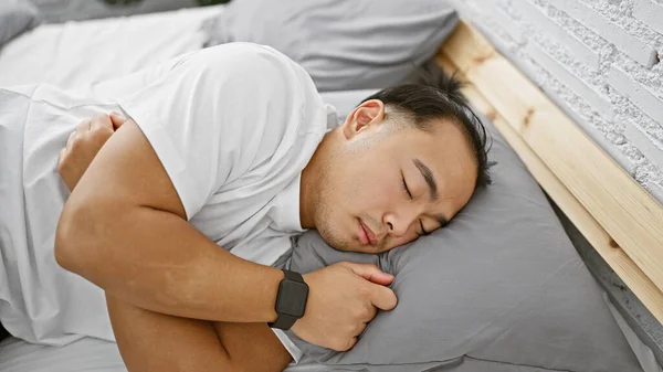 Handsome young chinese man in pajamas, comfortably asleep, tired yet relaxed, lying in the cozy sanctuary of his bedroom, home, a personification of relaxation indoors in the morning.