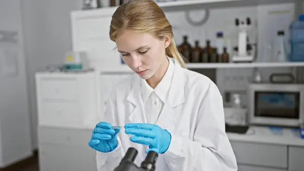 Mladá Blondýna Bílém Laboratorním Plášti Provádí Výzkum Mikroskopem Moderním Laboratorním — Stock fotografie