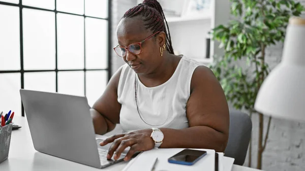 アフリカ系アメリカ人女性労働者がビジネスに興奮する 彼女のラップトップで熱心に働いているこの上司の女性は 彼女のオフィスで成功とプロフェッショナリズムを体現しています — ストック写真