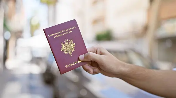Hand Holding French Passport Sunlit City Street Suggesting Urban Travel — Stock Photo, Image