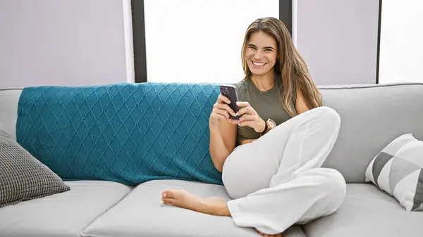 Junge Schöne Hispanische Frau Sitzt Mit Smartphone Auf Dem Sofa — Stockfoto