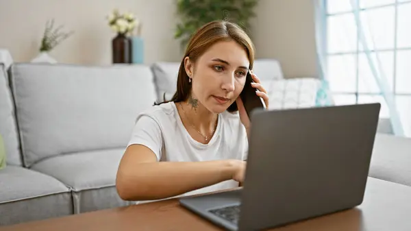 Akıllı Telefondan Konuşan Genç Bir Kadın Dizüstü Bilgisayarla Evde Oturuyor — Stok fotoğraf