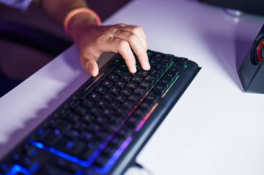 Oyun odasında bilgisayar klavyesi kullanan beyaz bir genç.