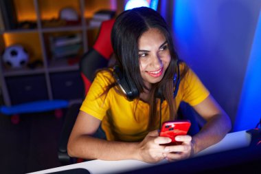 Oyun odasında bilgisayar ve akıllı telefon kullanan güzel bir Arap kadını.