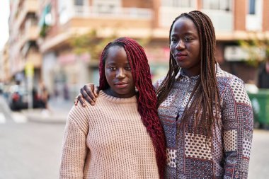 Afrika kökenli Amerikalı kadın arkadaşlar sokakta birbirlerine ciddi bir şekilde sarılıyorlar.