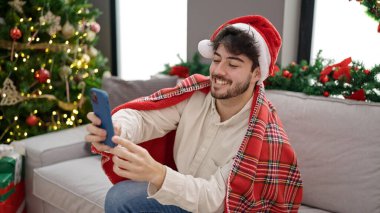 Genç İspanyol adam Noel 'i kutluyor. Evde akıllı telefondan selfie çekiyor.