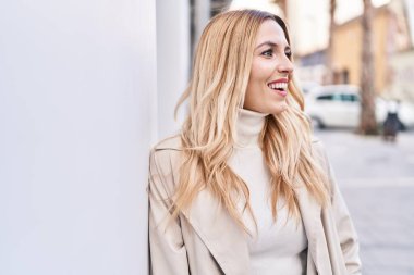 Young blonde woman smiling confident looking to the side at street