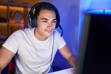 Oyun odasında bilgisayar kullanarak video oyunu oynayan İspanyol asıllı genç adam.