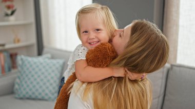Mutlu Kafkas anne ve kızı rahatça sarılıyor, oyuncak bir maymunu tutuyor, rahat rahat evlerinde oturuyorlar.