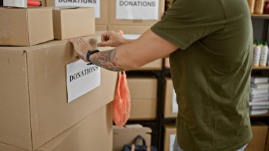 Depodaki bir adam gönüllü ya da hayır işi olduğunu ima ederek bağış etiketli kutular düzenler..
