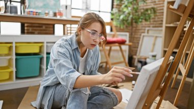 Young woman artist sitting on floor drawing at art studio