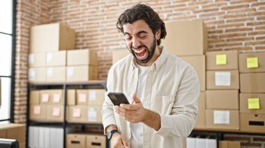 Genç bir İspanyol iş adamı ofiste kutlama yapmak için akıllı telefon kullanıyor.