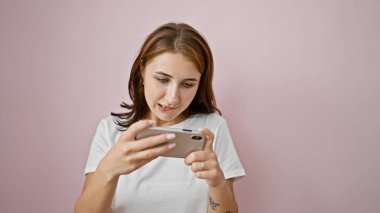 İzole edilmiş pembe arka planda video oyunu oynayan genç bir kadın