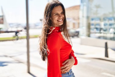 Young beautiful hispanic woman smiling confident looking to the side at street