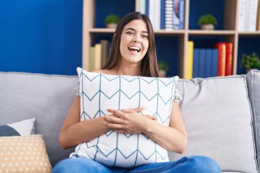 Kanepede oturmuş yastığa sarılan İspanyol kadın kahkahalarla gülüyor.. 