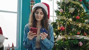 Akıllı telefon ve kredi kartıyla alışveriş yapan genç, güzel İspanyol kadın Noel 'i evde kutluyor.