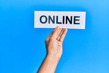 Hand of caucasian man holding paper with online word over isolated blue background