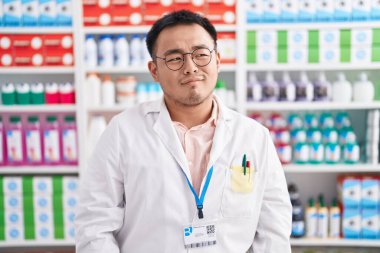 Eczanede çalışan Çinli genç adam gülümseyip yan tarafa bakıyor ve düşünüyor.. 