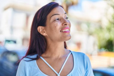 Young beautiful hispanic woman smiling confident looking to the side at street