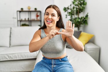 Genç ve güzel İspanyol kadın evdeki kanepede oturan sağırlarla iletişim kuruyor.