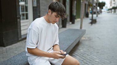 Havalı, genç İspanyol bir adam, telefonuna dalmış, günümüzün teknoloji meraklısı gençlik yaşam tarzının sıradan bir portresini çiziyor.