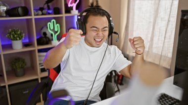 Muzaffer genç Çin flaması, kulaklıklar takılmış, odada muzaffer oyun gecesi kutlanıyor, teknoloji ve dijital eğlence ile dolu.