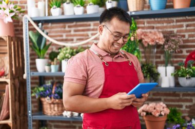 Young chinese man florist smiling confident using touchpad at florist