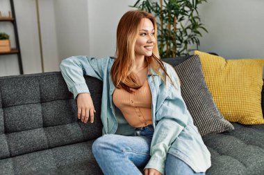 Kafkasyalı genç bir kadın evdeki kanepede kendinden emin bir şekilde oturuyor.