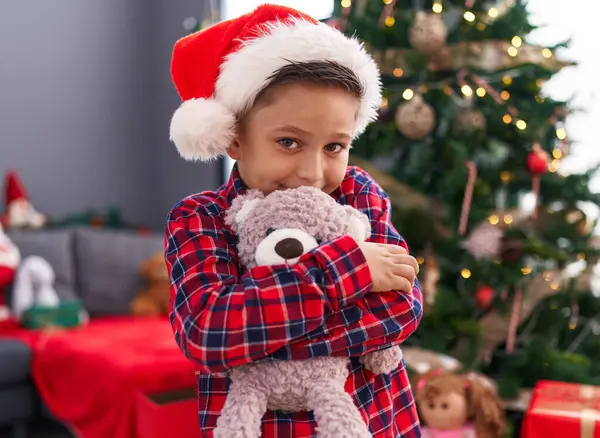 Suloinen Latino Poika Halaus Nallekarhu Seisoo Joulukuusi Kotona — kuvapankkivalokuva