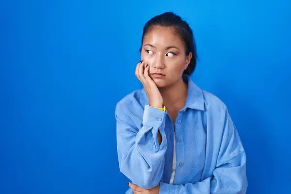 Mavi Arka Planda Duran Asyalı Genç Bir Kadın Gergin Gergin — Stok fotoğraf