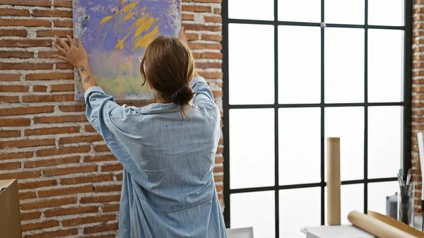 Young woman artist hanging draw on wall at art studio
