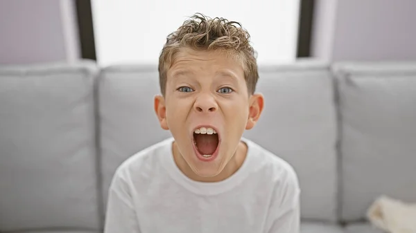 Adorable Blond Boy Sitting Sofa Home Expressing Loud Frustration Anger — Stock Photo, Image