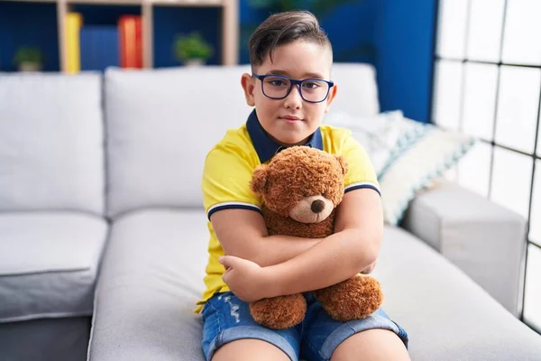 Adorable Hispanic Boy Hugging Teddy Bear Sitting Sofa Home — Stockfoto